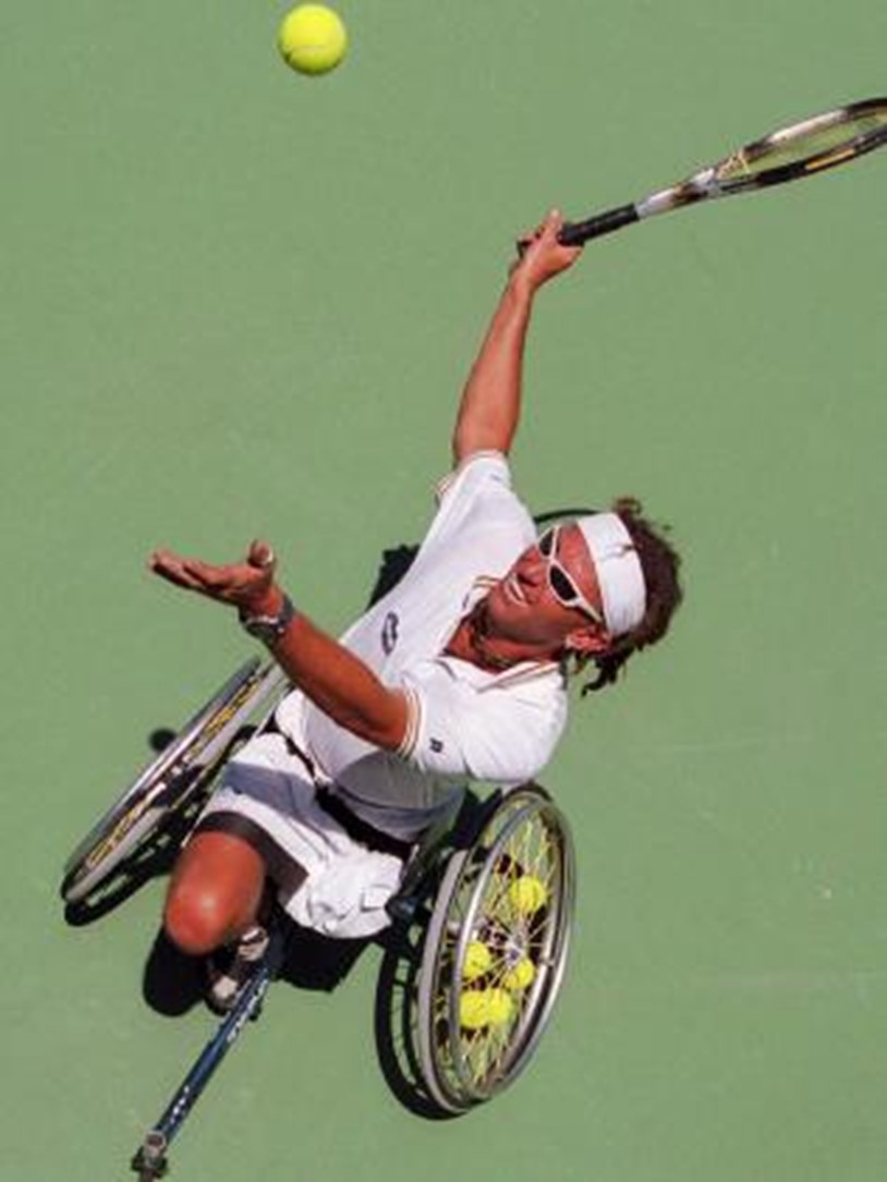 a man in white tennis clothes playing wheel chair tennis