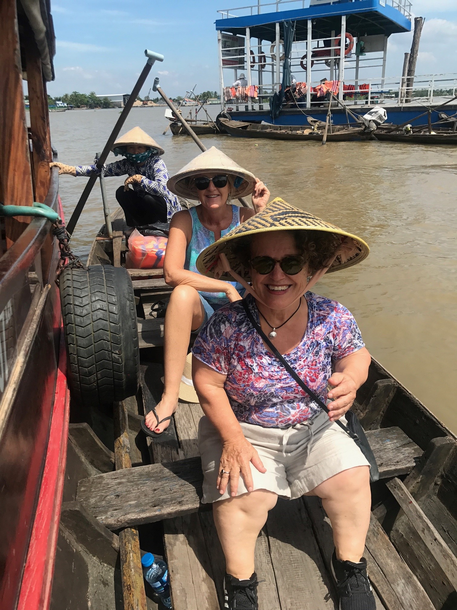 three women in a traditional boat in Vietnam wearing traditional Asian cooli hats