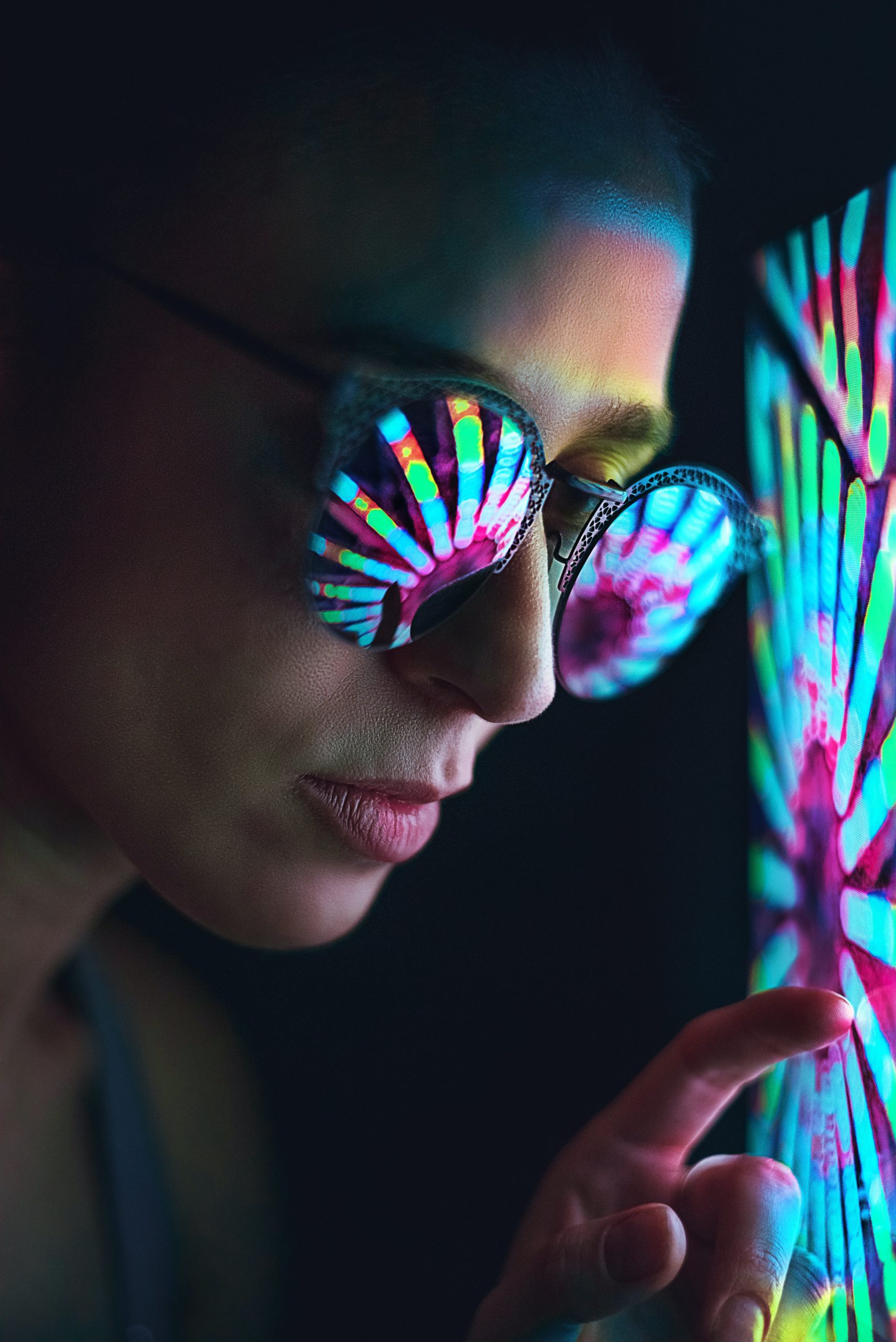 person wearing sunglasses with colourful lights reflected in the glasses